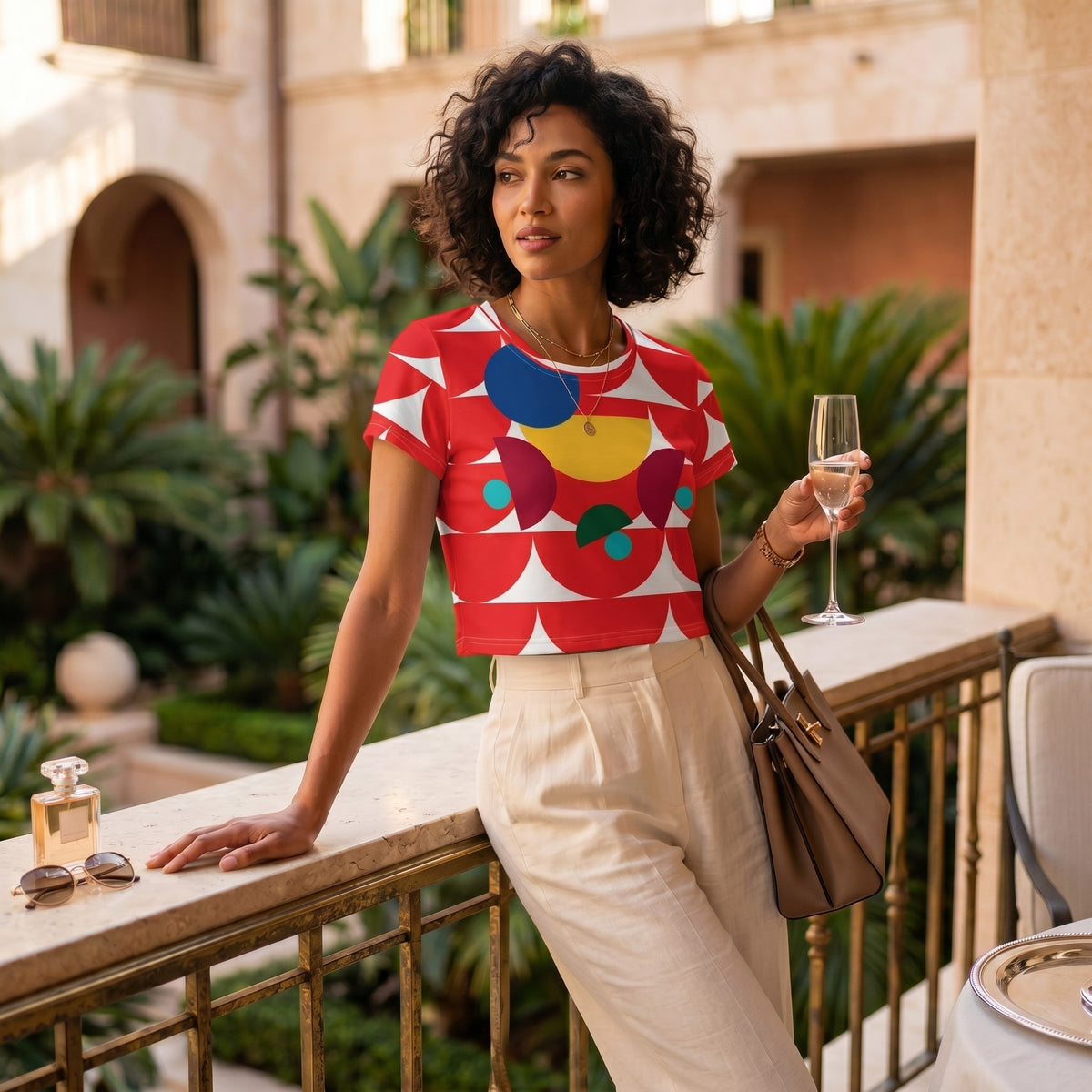 Good Wishes 365 crop tee with red geometric mushroom print worn by a woman holding a glass on a balcony