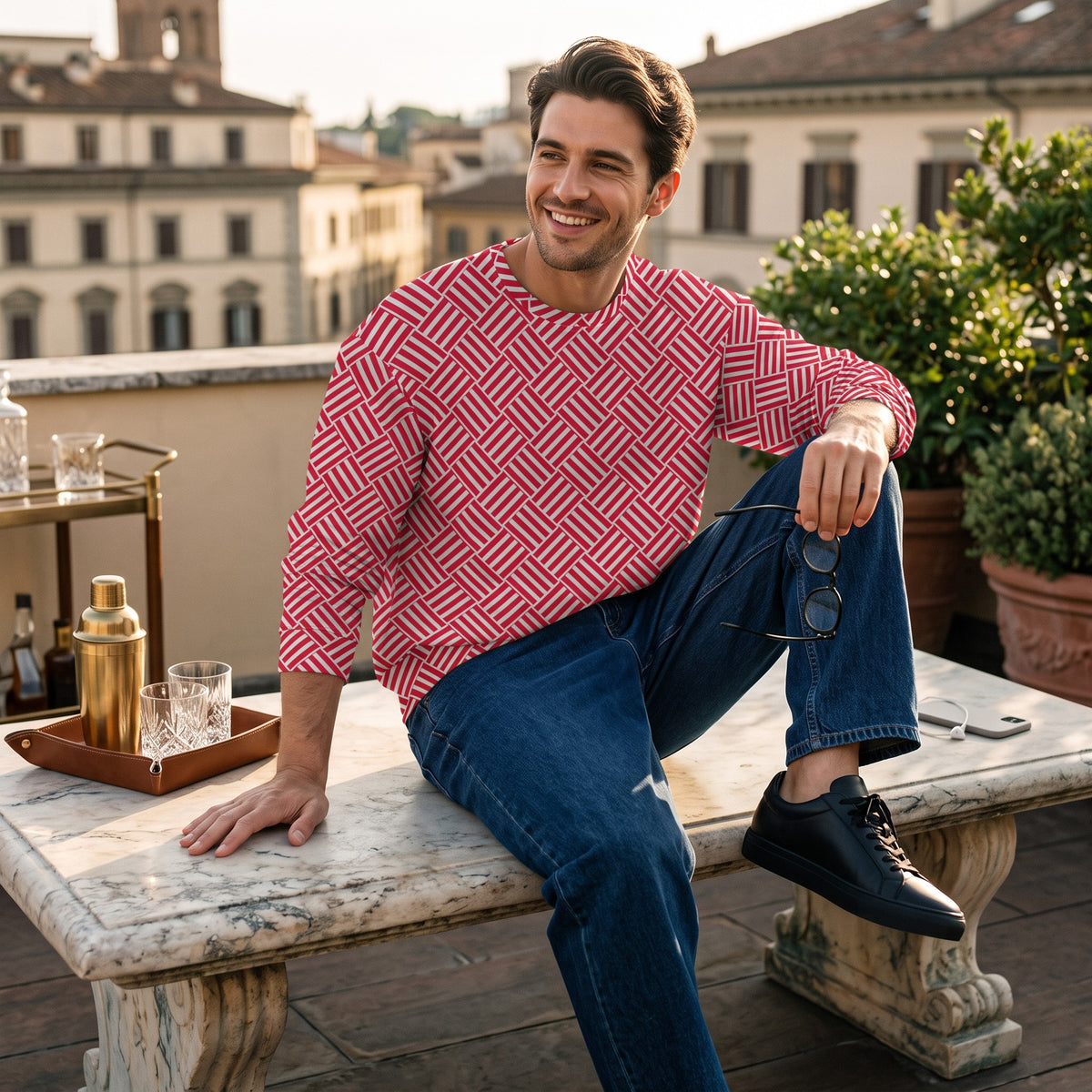 Good Wishes 365 unisex sweatshirt with a red and white geometric basketweave print, worn by a man on a rooftop terrace.