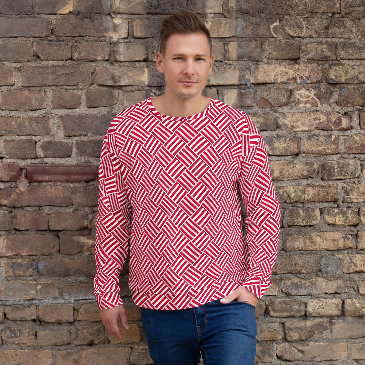 Good Wishes 365 unisex sweatshirt with a red and white geometric basketweave print worn by a man against a brick wall