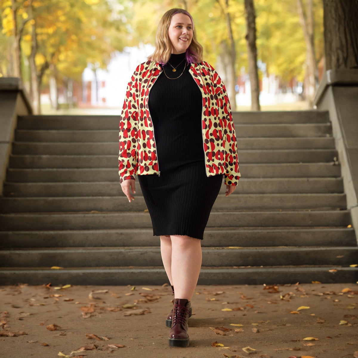 Woman wearing a Good Wishes 365 bomber jacket with brown polka dots and red semi-circles over a black ribbed dress