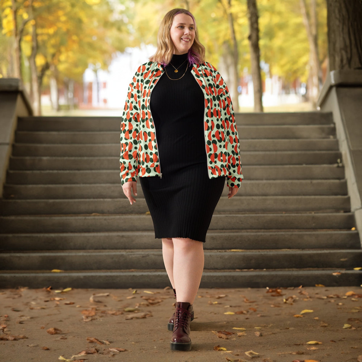 Good Wishes 365 unisex bomber jacket with green polka dots and orange semi-circles worn by a woman on outdoor stairs.