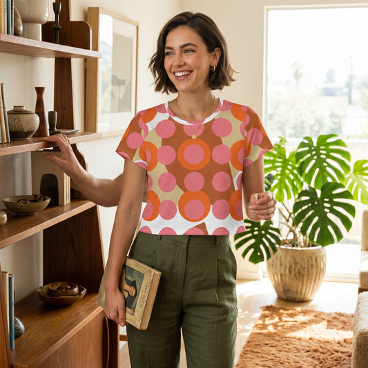 Good Wishes 365 retro mod crop tee with pink and orange polka dots worn by a smiling woman in a bright living room.