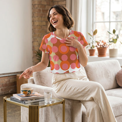 Good Wishes 365 retro mod polka dot crop tee in pink and orange worn by a laughing woman in a bright living room