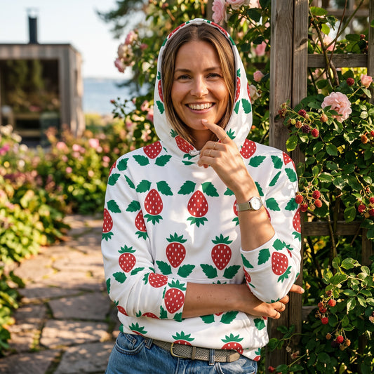 Good Wishes 365 unisex hoodie with strawberry print, white recycled fabric, and adjustable hood in a garden setting.