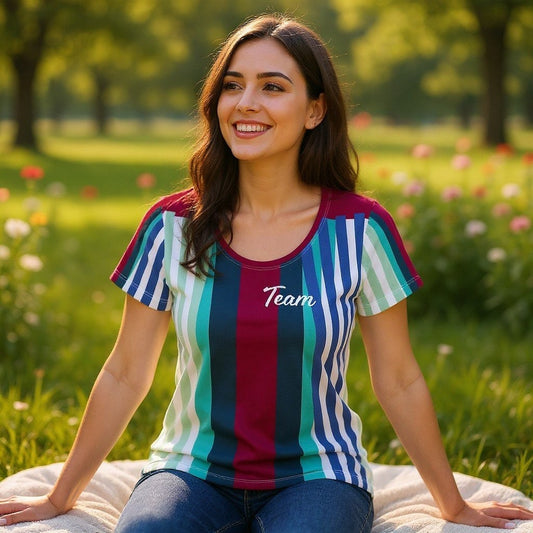 Good Wishes 365 women's athletic t-shirt with burgundy, blue, and teal vertical stripes and Team graphic in a park.