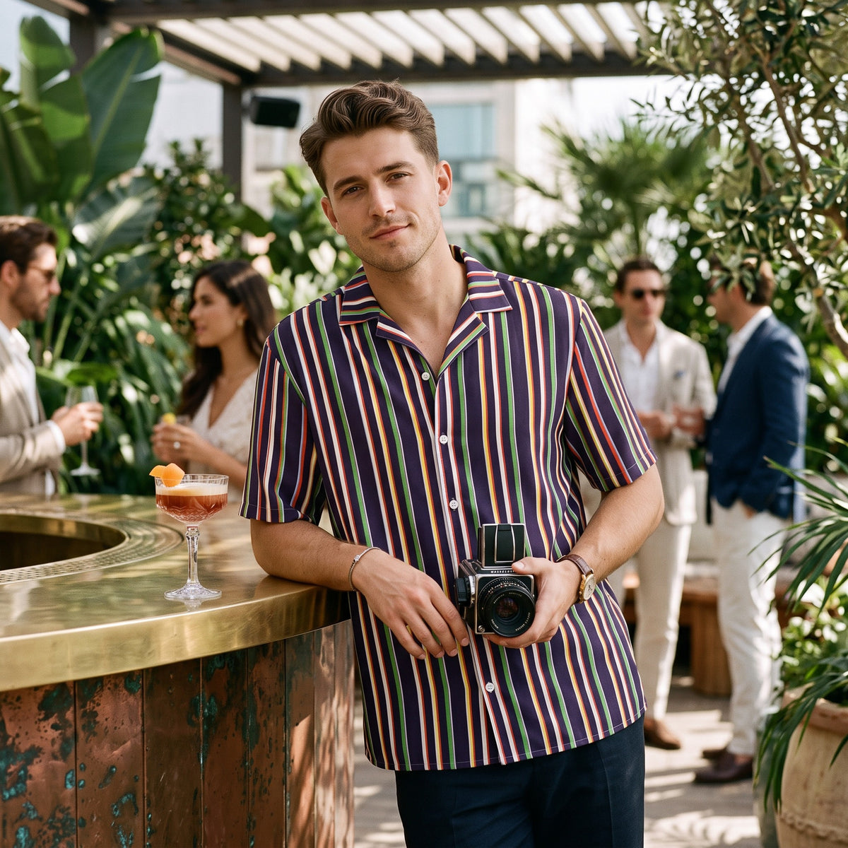 Good Wishes 365 unisex oversized button shirt with a colorful vertical stripe pattern, worn by a man at a party.