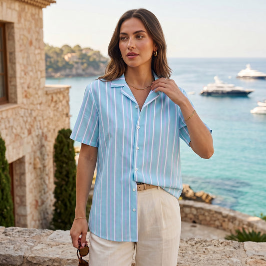 Good Wishes 365 oversized button-down shirt in light blue and white stripes, worn by a woman near the ocean.