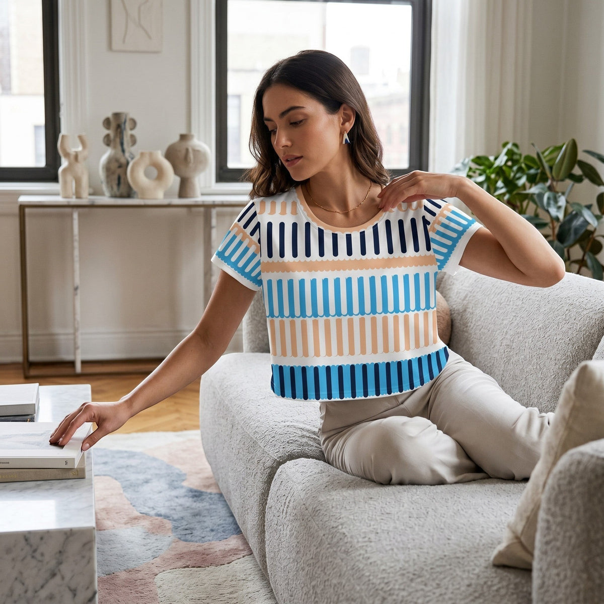 Woman wearing a Good Wishes 365 crop tee with a blue and beige striped pattern, sitting on a textured sofa.