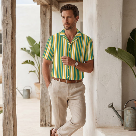 Good Wishes 365 men's yellow and blue vertical striped short sleeve camp collar shirt worn with beige linen trousers.