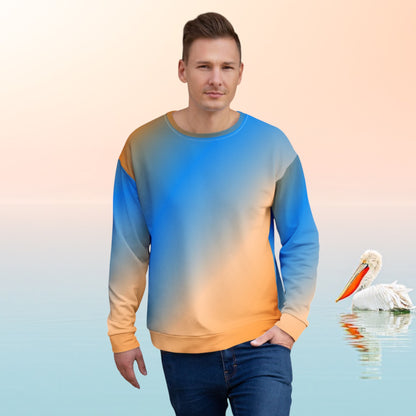 Good Wishes 365 unisex sweatshirt with a vibrant blue and orange sunset gradient print worn by a man against a brick wall