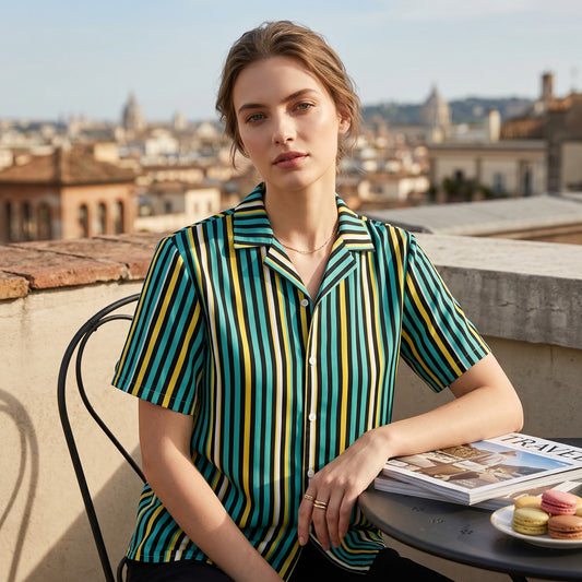 Good Wishes 365 teal and yellow striped short sleeve button-up shirt with UPF50+ protection worn by a woman on a terrace.