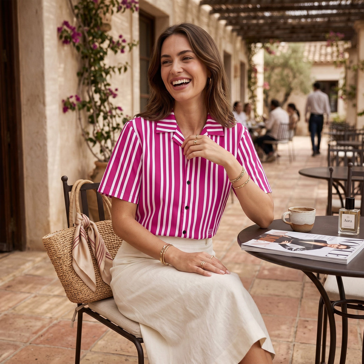 Good Wishes 365 violet and red vertical striped short sleeve camp collar shirt worn by a smiling woman at a cafe.
