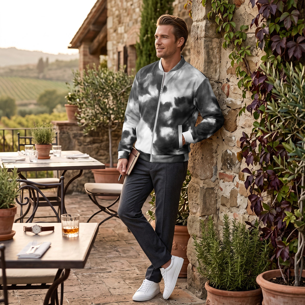 Good Wishes 365 unisex black and white watercolor print bomber jacket with silver zipper worn by a man on a patio.