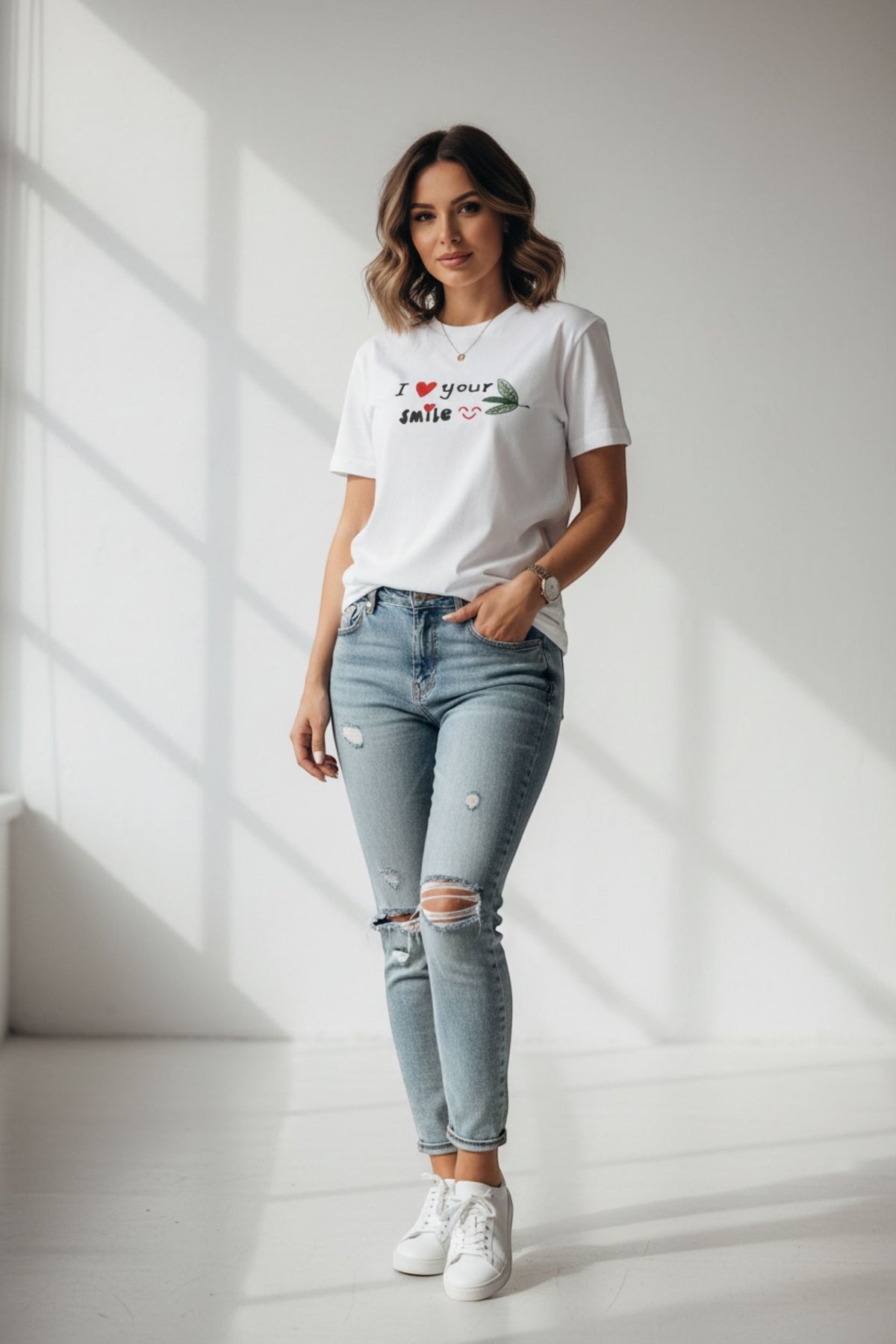 Good Wishes 365 white crewneck t-shirt with I Love Your Smile graphic, worn by a woman with distressed blue jeans.