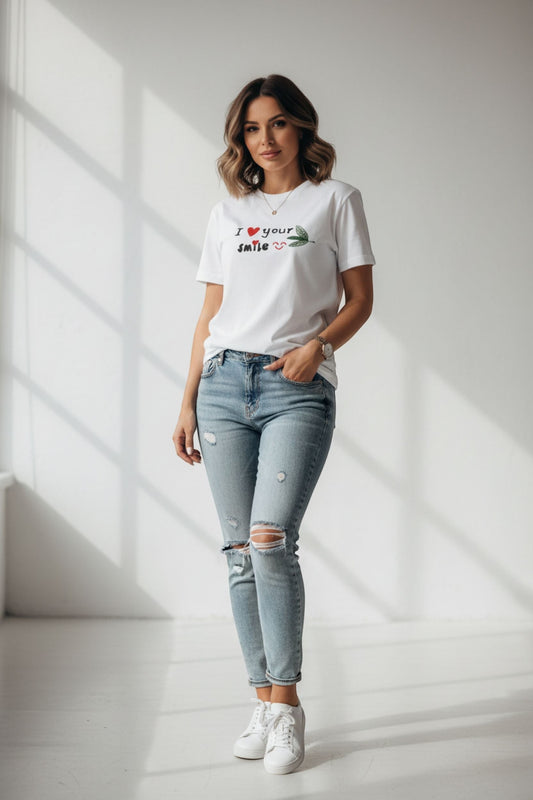 Good Wishes 365 white crewneck t-shirt with I Love Your Smile graphic, worn by a woman with distressed blue jeans.