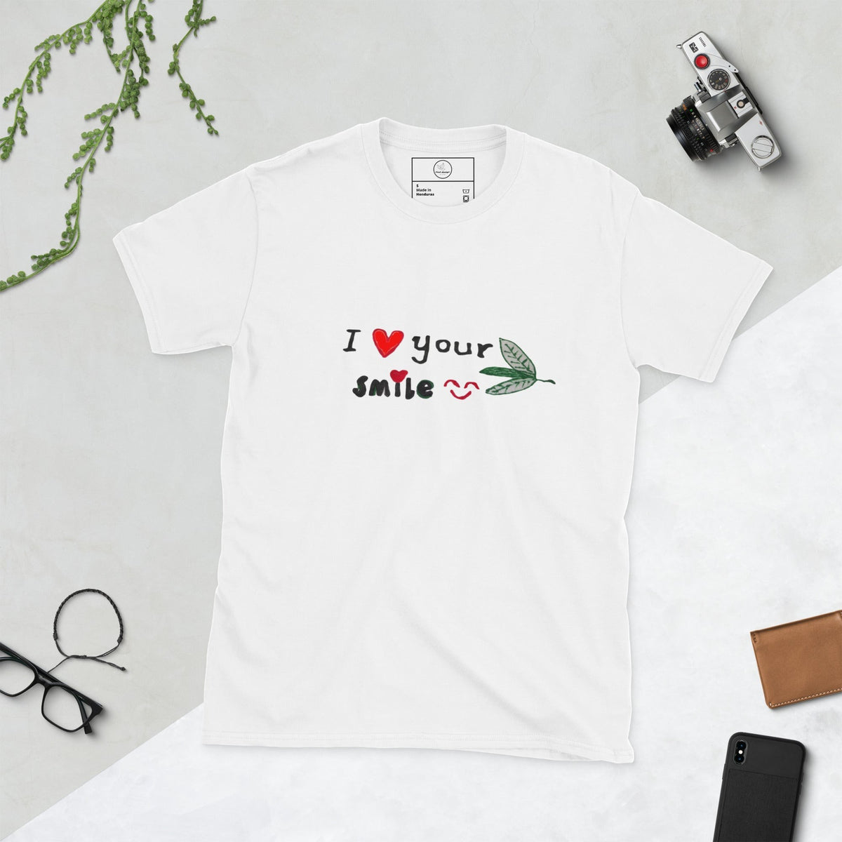 Good Wishes 365 white unisex crewneck t-shirt featuring an I Love Your Smile graphic with red hearts and a green leaf.