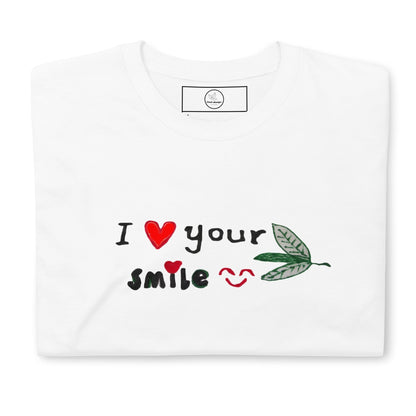 Good Wishes 365 white unisex crewneck t-shirt with I Love Your Smile graphic, red hearts, and green leaf accents.
