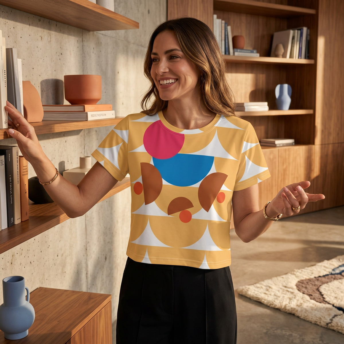 Good Wishes 365 yellow crop tee with geometric mushroom graphic print, worn by a smiling woman in a modern home library.