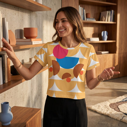 Good Wishes 365 yellow crop tee with geometric mushroom graphic print, worn by a smiling woman in a modern home library.