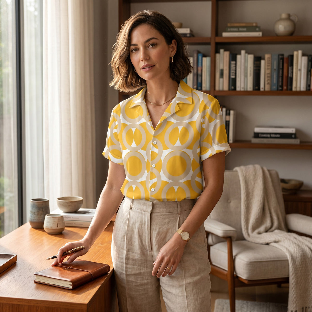 Good Wishes 365 yellow retro geometric print button-up shirt with camp collar worn by a woman in a home office.