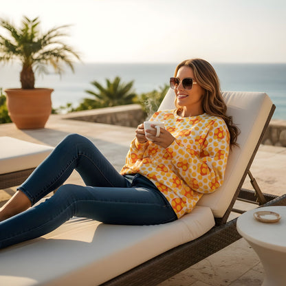 Good Wishes 365 yellow geometric print recycled sweatshirt worn by a woman relaxing on a lounge chair with coffee.